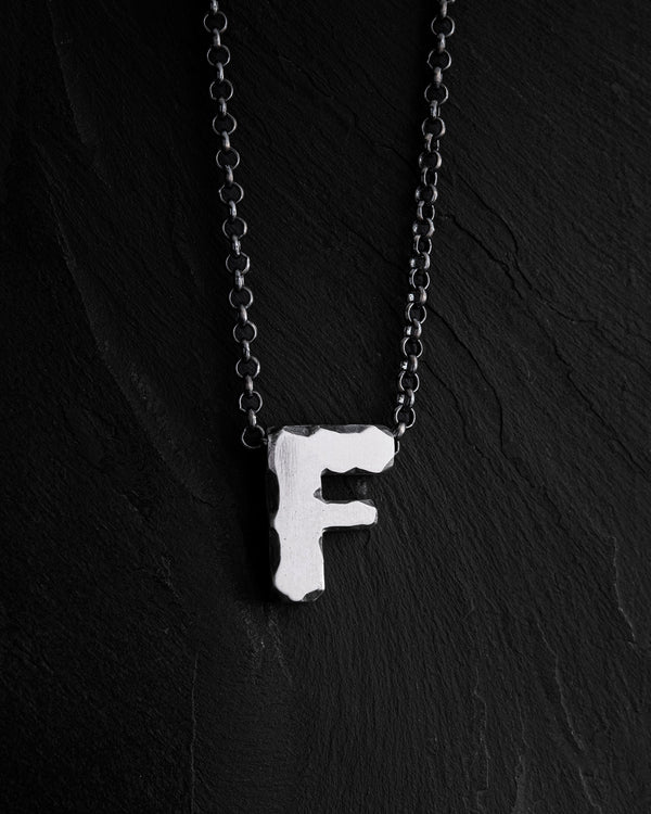 Anhänger mit dem Buchstaben F an einer Kette